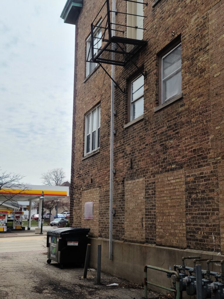 A side view of an apartment building with emergency fire escape ladder